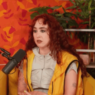A Woman With Red Hair Is Sitting In Front Of A Microphone And Talking . GIF