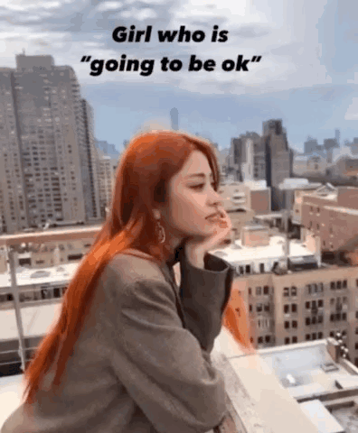 A Woman With Red Hair Is Sitting On A Balcony Overlooking A City With A City Skyline In The Background . GIF