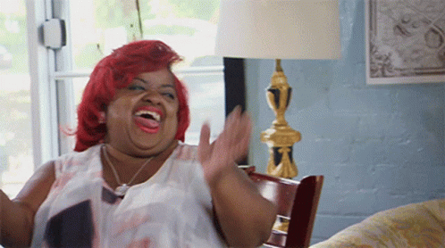 A Woman With Red Hair Is Sitting On A Couch And Laughing GIF