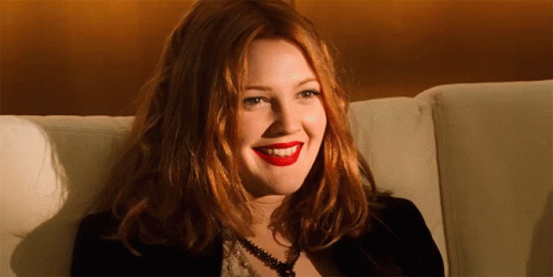 A Woman With Red Hair Is Sitting On A Couch Smiling GIF