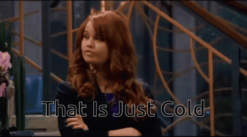 A Woman With Red Hair Is Sitting With Her Arms Crossed And The Words That Is Just Cold Behind Her GIF