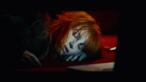 A Woman With Red Hair Is Sleeping On A Red Couch GIF