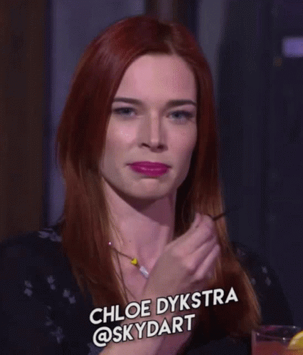 A Woman With Red Hair Is Smiling And Has The Name Chloe Dykstra @Skydart On The Bottom GIF