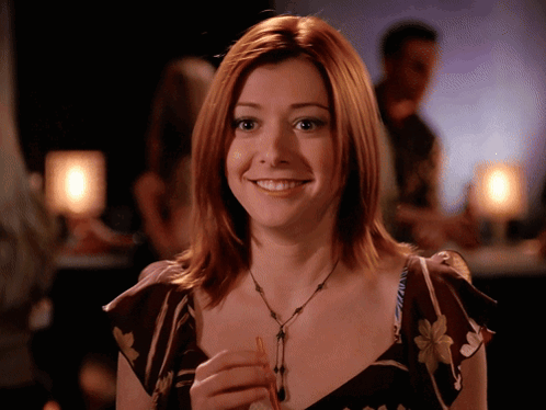 a woman with red hair is smiling and holding a small object