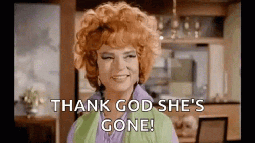 A Woman With Red Hair Is Smiling And Saying `` Thank God She 'S Gone '' In A Kitchen . GIF