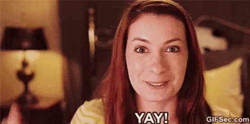 A Woman With Red Hair Is Smiling And Says Yay ! GIF