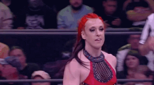 A Woman With Red Hair Is Standing In A Wrestling Ring . GIF