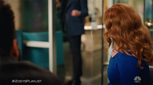 A Woman With Red Hair Is Standing In Front Of A Sign That Says #Zoeysplaylist GIF