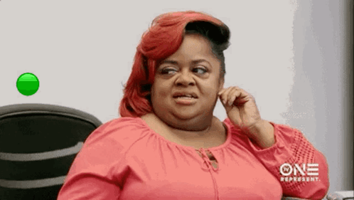 A Woman With Red Hair Is Talking On A Cell Phone While Sitting In A Chair . GIF