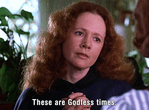 A Woman With Red Hair Is Talking To A Man And Says " These Are Godless Times " GIF