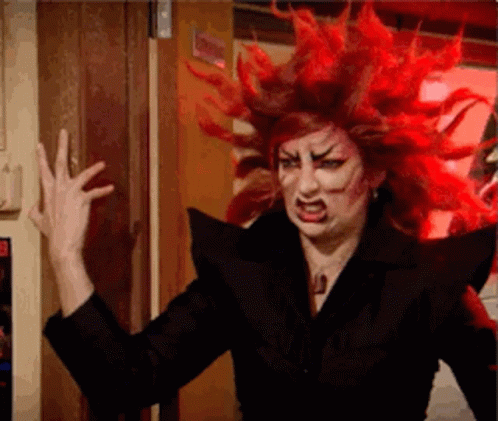 A Woman With Red Hair Is Wearing A Black Jacket And Making A Funny Face . GIF