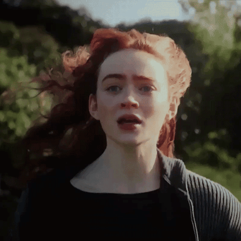 A Woman With Red Hair Is Wearing A Black Shirt GIF