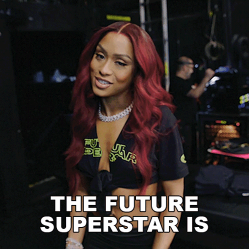 A Woman With Red Hair Is Wearing A Black Shirt That Says " The Future Superstar Is " GIF