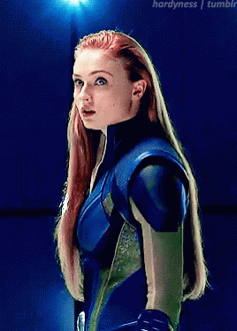 A Woman With Red Hair Is Wearing A Blue And Green Suit GIF