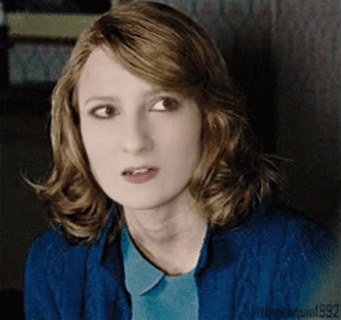 A Woman With Red Hair Is Wearing A Blue Shirt And A Blue Sweater GIF