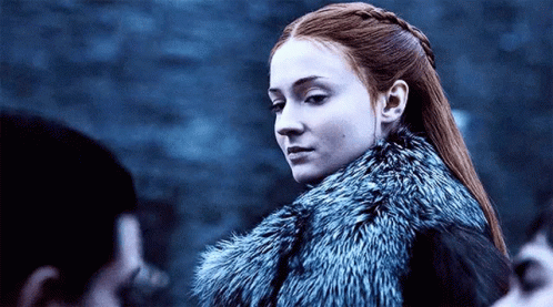 A Woman With Red Hair Is Wearing A Fur Coat And Looking At The Camera . GIF