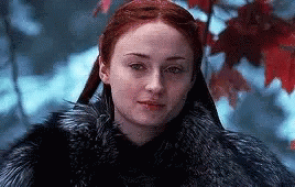 A Woman With Red Hair Is Wearing A Fur Coat And Standing In The Snow . GIF