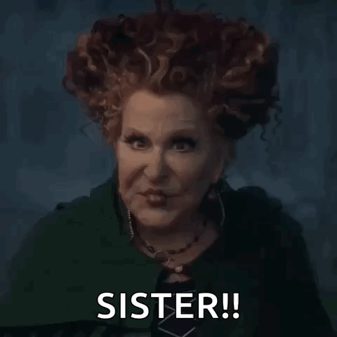 A Woman With Red Hair Is Wearing A Green Cape And A Necklace And Says `` Sister '' . GIF