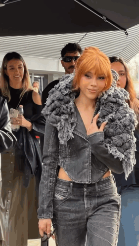 A Woman With Red Hair Is Wearing A Grey Jacket GIF