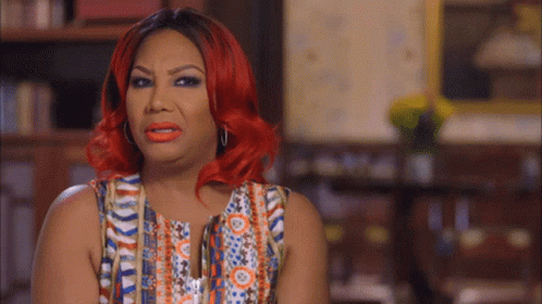 A Woman With Red Hair Is Wearing A Multicolored Top GIF