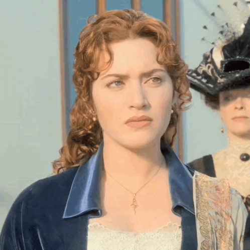 A Woman With Red Hair Is Wearing A Necklace That Has A Key On It GIF