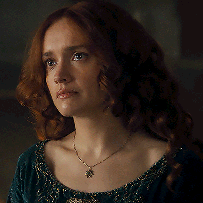 A Woman With Red Hair Is Wearing A Necklace With A Leaf Pendant GIF