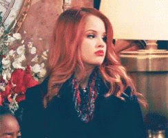 A Woman With Red Hair Is Wearing A Scarf And A Black Jacket GIF
