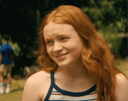 A Woman With Red Hair Is Wearing A Striped Tank Top And Smiling GIF
