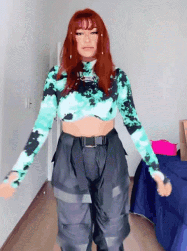 a woman with red hair is wearing a tie dye crop top and cargo pants