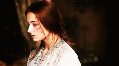A Woman With Red Hair Is Wearing A White Blouse GIF