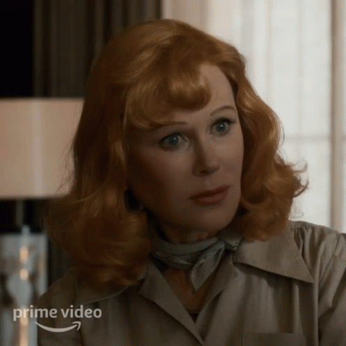 A Woman With Red Hair Is Wearing A White Shirt And A Scarf And The Word Prime Video Is On The Bottom GIF