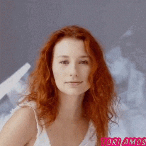 A Woman With Red Hair Is Wearing A White Tank Top And The Word Toriamos Is On The Bottom Right GIF