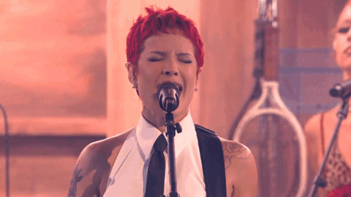 A Woman With Red Hair Singing Into A Microphone With Her Eyes Closed GIF
