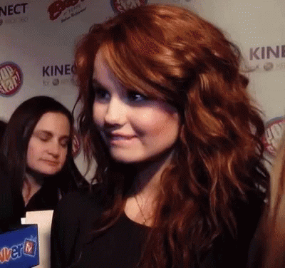A Woman With Red Hair Stands In Front Of A Wall That Says Kinect On It GIF