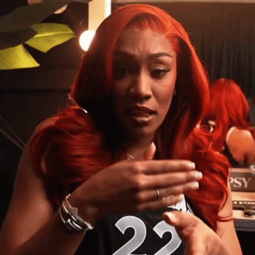 A Woman With Red Hair Wearing A Black Jersey With The Number 22 On It GIF