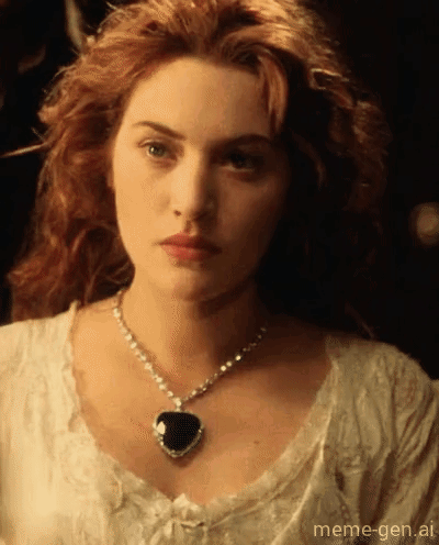 A Woman With Red Hair Wearing A Heart Shaped Pendant GIF