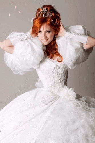A Woman With Red Hair Wearing A White Dress And A Tiara GIF