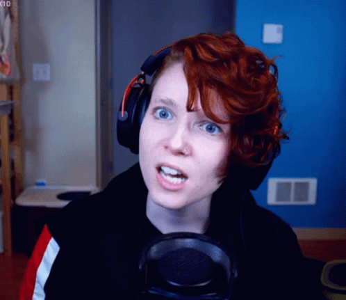 A Woman With Red Hair Wearing Headphones Looks At The Camera GIF