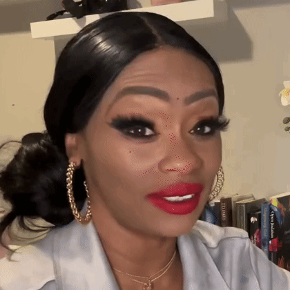 a woman with red lipstick and gold hoop earrings is making a funny face .