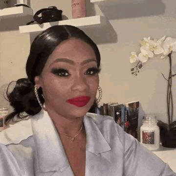 a woman with red lipstick and hoop earrings is taking a selfie in a room .