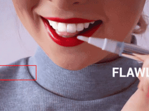 A Woman With Red Lipstick And White Teeth Is Holding A Whitening Pen GIF