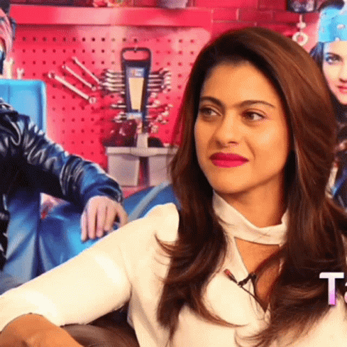 A Woman With Red Lipstick Is Sitting In Front Of A Sign That Says T. GIF