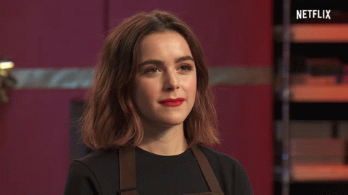 A Woman With Red Lipstick Is Standing In Front Of A Sign That Says Netflix On It GIF