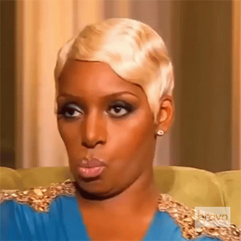 A Woman With Short Blonde Hair Is Sitting On A Couch With Bravo Written On The Bottom Right GIF