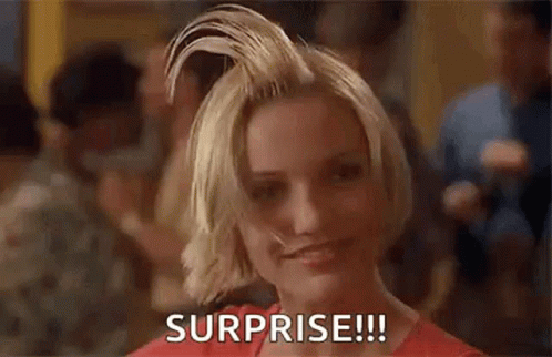 A Woman With Short Blonde Hair Is Smiling And Holding Her Hair Up In The Air . GIF