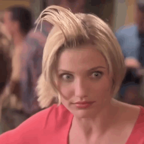 A Woman With Short Blonde Hair Is Wearing A Red Shirt And Looking At The Camera . GIF