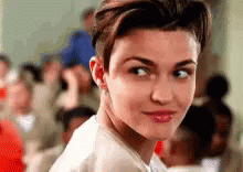 A Woman With Short Hair Is Looking At The Camera In Front Of A Crowd . GIF