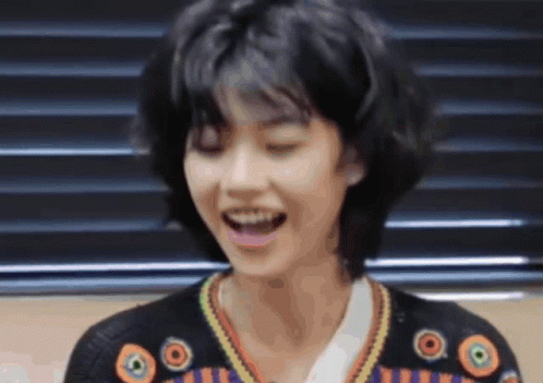 A Woman With Short Hair Is Smiling With Her Eyes Closed GIF