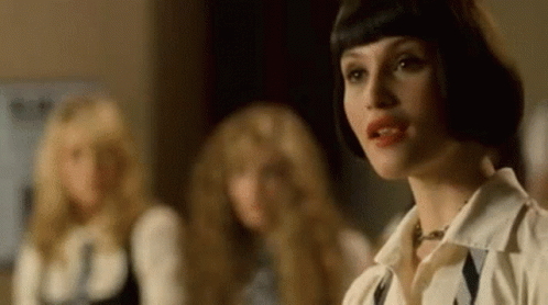 A Woman With Short Hair Is Standing In Front Of A Group Of Women . GIF