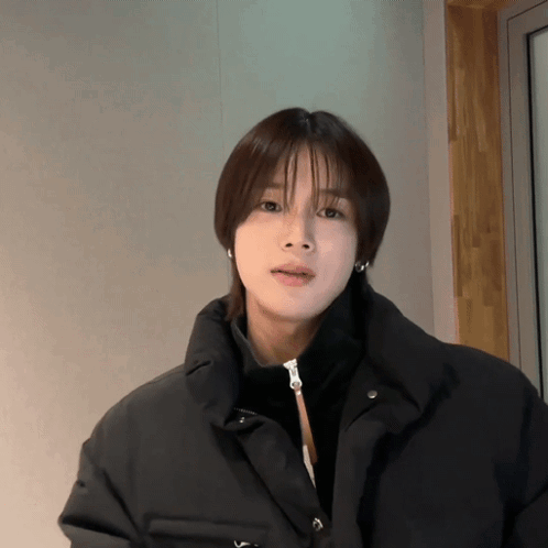 A Woman With Short Hair Is Wearing A Black Jacket And Earrings GIF